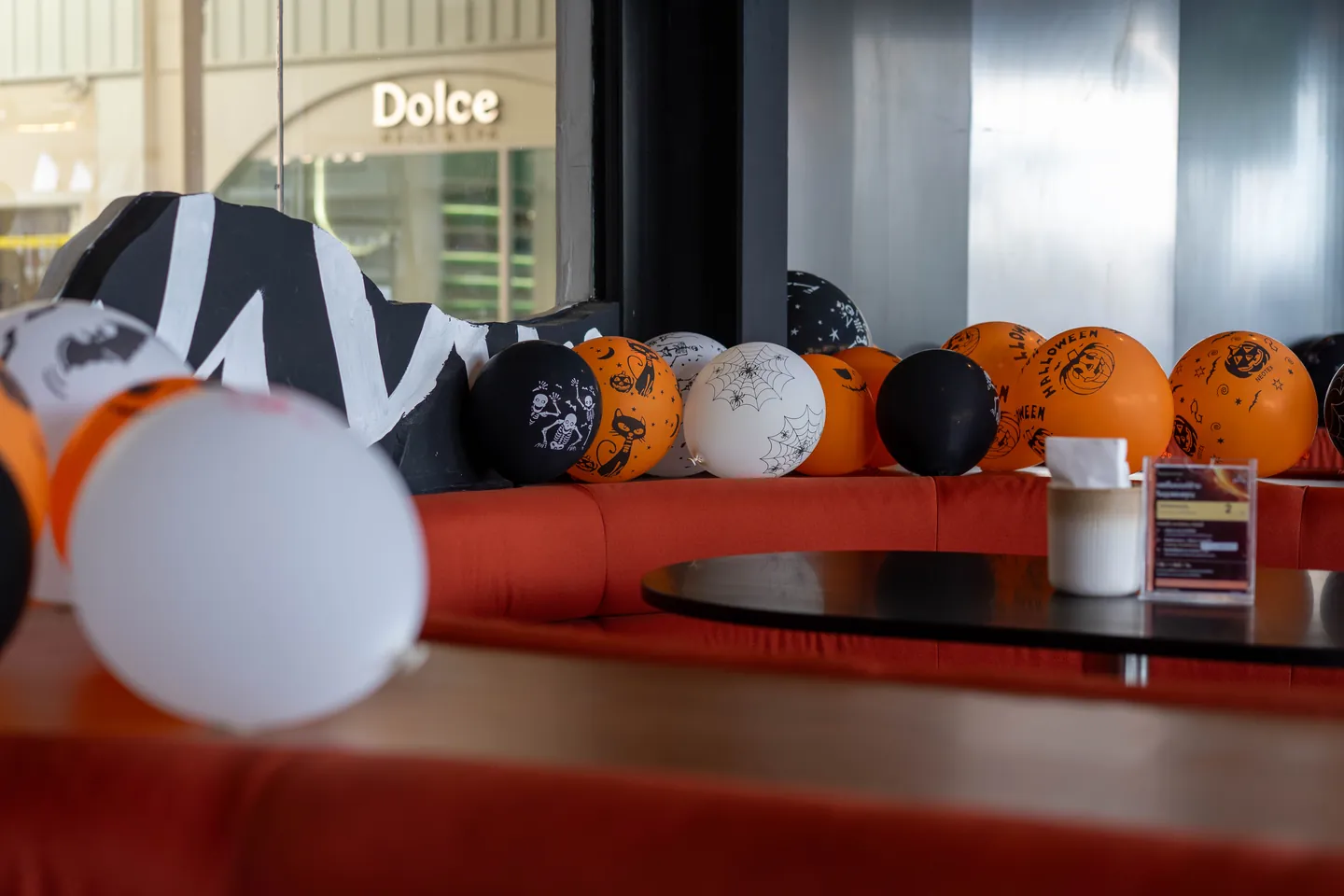 ลูกโป่ง Halloween สีส้ม ดำ ขาว บนโซฟาแดง ที่ Underdog สาขาพัฒนาการ
